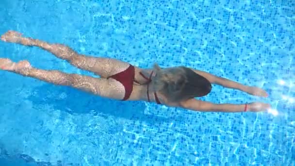 Draufsicht auf eine unkenntliche Frau, die unter Wasser in einem Pool mit transparentem, klarem Wasser schwimmt. Junges Mädchen entspannt sich während der Sommerferien beim Schwimmen im Becken. Konzept der Sommerferien. Langsam mo Close Up — Stockvideo