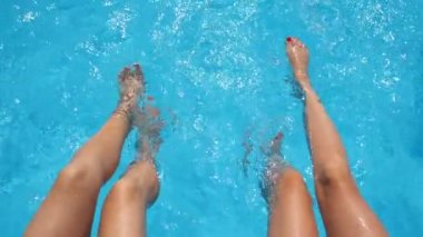 Kadın bacaklarının manzarası otel havuzunda berrak su sıçratıyor. Havzanın kenarında oturan iki arkadaş güneşli bir günde tatilin tadını çıkarıyorlar. Yaz tatili ya da tatil kavramı. Yavaş çekim