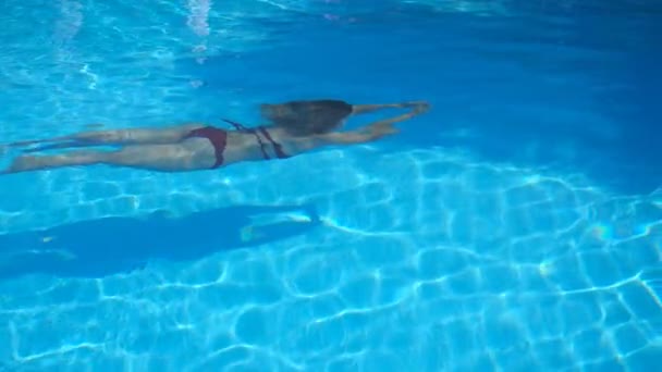 Felismerhetetlen nő fürdőruhában, aki a víz alatt úszik kristálytiszta vízben. Fiatal lány pihen a medencében úszás közben. A nyári vakáció fogalma. Lassú mozgás Oldalnézet — Stock videók