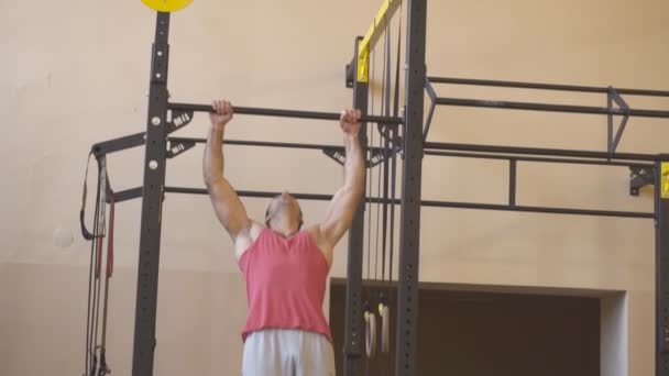 Esportista muscular fazendo exercícios na barra horizontal no ginásio. Atleta forte fazendo pull ups durante o treino. Jovem ginasta em sportswear formação interior. Conceito de esporte e estilo de vida ativo. Fechar — Vídeo de Stock