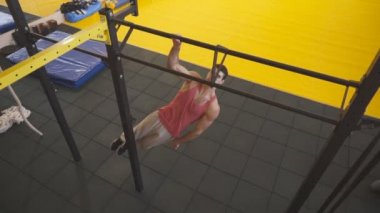 Spor salonunda tek elle barfiks çeken güçlü bir sporcu. Yatay çubukta genç sporcu eğitimi. Kas sporcusu egzersiz sırasında güç egzersizleri yapıyor. Sportif yaşam tarzı kavramı. Üst görünüm