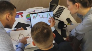 Profesyonel yöneticiler satış sonuçlarının grafiklerini ofislerinde bilgisayar ekranlarında grafikle karşılaştırıyorlar. İş toplantılarında finansal raporları analiz eden bir grup genç iş arkadaşı. Üst görünüm