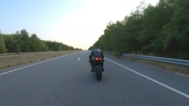 Motorcu, boş köy yolunda motorsikletle hızlanıyor. Sonbahar otobanında modern spor motosikletinde hızlı giden bir adam. Yolculuk sırasında bisiklet süren adam. Özgürlük ve macera kavramı. Hava görüntüsü