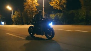 Miğferli genç adam şehir caddesinde modern siyah spor motosikletle hızlı gidiyor. Motosikletli, boş yolda motosikletiyle yarışıyor. Bisikletli adam. Özgürlük ve hobi kavramı. Kapat.