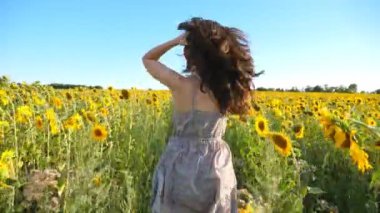 Sarı ayçiçeği tarlasında koşan tanınmamış esmer. Genç bir kadın yaz güneşli bir günde çayırda koşarken eğleniyor. Mutluluk ve özgürlük kavramı. Yavaş çekim Arka plan