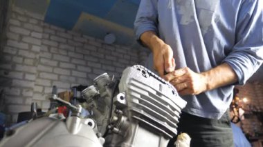 Tanımlanamayan profesyonel tamirci bir aracın motorunu tamir ediyor. Otomobil ustası garajda ya da atölyede motor tamir ediyor. Arabalara ya da motorsikletlere bakan bir adam. Yavaş çekim Düşük görünüm