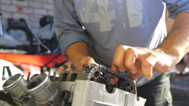 Вид на розібраний мотоцикл. Руки професійного механічного ремонту двигуна. Реконструктор працює в гаражі або майстерні. Людина займалася обслуговуванням автомобілів або мотоциклів. Закріпіть Доллі — стокове відео