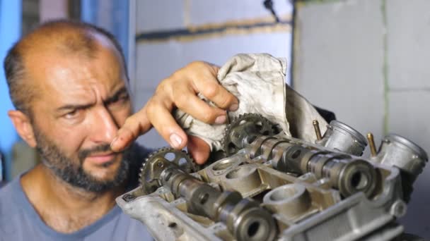 Aracın motorunu tamir eden profesyonel tamircinin portresi. Dikkatli tamirci otomobil motorunu tamir ediyor. Otomobil ustası işini garajda ya da atölyede yapıyor. Adam otomatik servise başladı. Yavaş çekim — Stok video