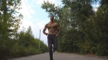 Yakışıklı sporcu arka planda güzel manzara ile yol boyunca hızlı sprint. Kablosuz kulaklıklı genç kaslı adam doğada patikaboyunca koşuyor. Sağlıklı aktif yaşam tarzı. Düşük görünüm