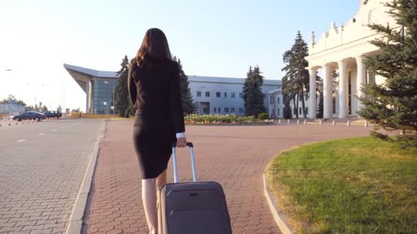 スーツケース付きの認識できないビジネス女性が空港まで歩いて出張に行きます。通りに沿って彼女の荷物を踏んでハイヒールの靴の女性。旅行のコンセプト。戻るビュースローモーション閉じる — ストック動画