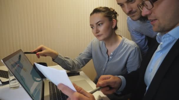 Responsabili professionali che confrontano il grafico dei risultati delle vendite su carta con il grafico sullo schermo del computer in ufficio. Gruppo di giovani colleghi che esaminano le relazioni finanziarie durante le riunioni di lavoro al chiuso. Dolly ha sparato. — Video Stock