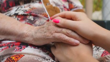 Güzel manikürlü genç kadın kolları yaşlı bir kadını rahatlatıyor. Torunumla büyükannem dışarıda vakit geçiriyorlar. Şefkatli ve sevgi dolu bir kavram. Yavaşça kapat.