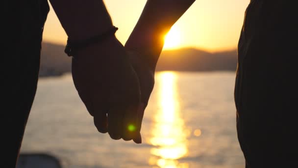 Silhouette de mains mâles et femelles se tenant l'une l'autre au coucher du soleil sur fond marin. Jeune couple joignant les bras en plein air. Concept d'amour et de bonheur. Fermer Vue arrière Vue arrière Mouvement lent — Video