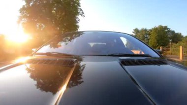 Arka planda günbatımı olan genç bir çift kırsal alanda araba geziyor. Mutlu çiftler yaz akşamları kırsal alanda iyi yolculuklar. Yolculuk ya da hafta sonu kavramı. Ön görünümü kapat