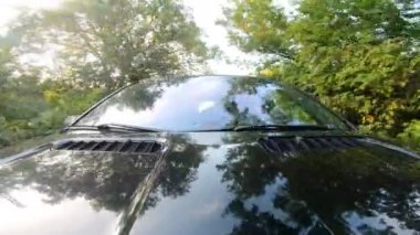 Genç çift kırsalda araba sürmekten zevk alıyor. Erkek arkadaş ve kız arkadaş yaz akşamı otomobille seyahat ediyorlar. Arka planda manzaralı otomobil sürüşü. Yolculuk konsepti. Ön görünüm