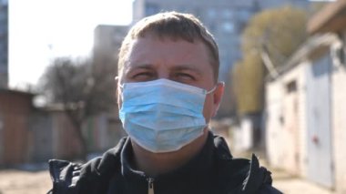 Tıbbi maskeli bir adamın portresi COVID-19 salgını sırasında şehir caddesinde duruyor. Dışarıdaki virüsten koruyucu maske takan adam. Coronavirüs salgınından sağIık ve güvenlik kavramı