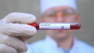 Doktor, Coronavirus 'a kan örneği veren bir test tüpü tutuyor. Koruyucu eldivenli sıhhiyenin eli laboratuarda kan örneklerini test ediyor. COVID-19 salgınından sağIık ve güvenlik kavramı. Kapat.