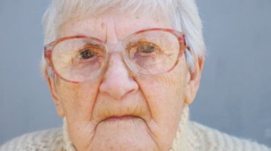 Gözlüklü yaşlı kadının portresi. Kameraya bakıp hüzünlü duygular gösteren buruşuk kadın emeklinin yüzünü kapat. Büyükannenin kederli yüz ifadesi. Olgun bir kadının bakışları