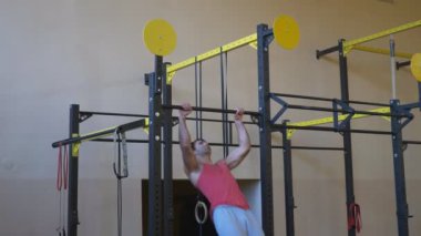 Genç sporcu spor salonunda yatay barda sıkı egzersizler yapıyor. Spor yaparken barfiks çeken güçlü bir jimnastikçi. Spor giyim antrenmanında kaslı sporcu. Spor ve aktif yaşam tarzı kavramı