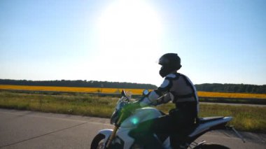 Kasklı bir adam otoyolda güçlü bir motorla hızlı gidiyor. Motosikletli doğa manzarasına karşı motosikletiyle yarışıyor. Koruyucu ekipmanlı adam yolculuğun tadını çıkarıyor. Macera ya da özgürlük kavramı