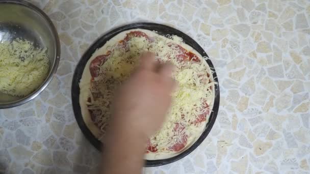 POV manliga händer kock sätta riven ost på bakverk med ingredienser i metall form vid köket. Chef gör en pepperoni pizza på träytan i köket. Matberedningskoncept. Ovanifrån Slow mo — Stockvideo