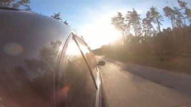 Kırsal bir yolda siyah otomobil hızla gidiyor. Güneşli bir yaz gününde otoyolda giden bir arabanın yanından bakış açısı. Otoyol boyunca hareket eden otomobil manzarası. Yolculuk konsepti