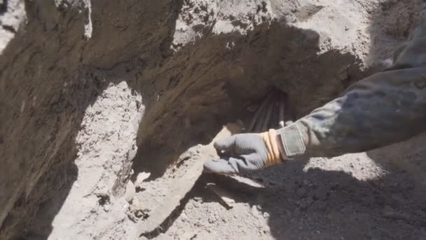 Arqueólogo encontrando cuchillo prehistórico en ruinas durante la excavación. Manos masculinas en guantes limpiando la suciedad del artefacto con un cepillo sobre el objeto. Concepto de arqueología. De cerca. — Vídeo de stock