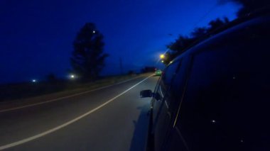 Geceleri kırsal yolda yarışan siyah jipin görüntüsü. Akşamları otobanda araba sürmek. Araç otoyol boyunca kırsal alanlardan hızla geçiyor. Trip ya da seyahat konsepti. POV