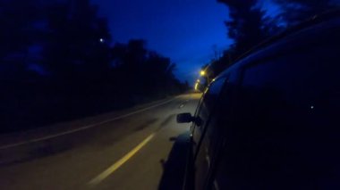 Geceleri kırsal yolda yarışan siyah jipin görüntüsü. Akşamları otomobille yola çıkıyoruz. Araç otoyol boyunca kırsal alanlardan hızla geçiyor. Trip ya da seyahat konsepti. POV