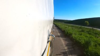 Güneşli bir günde asfalt yolda mal taşıyan bir kamyon. Kırsal bölgede hareket eden bir kamyon römorkundan diğerine. Hedefe giden ticari bir araba. Kargo taşıma konsepti. Yavaş çekim