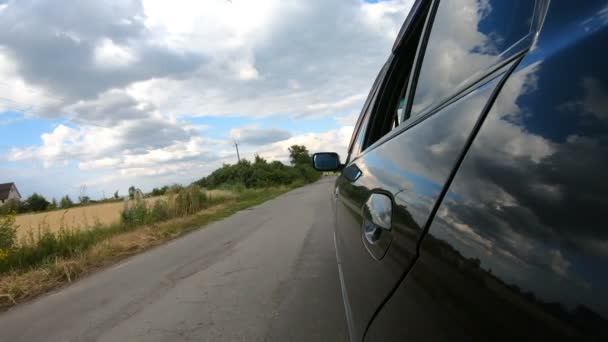 Точка зору з боку автомобіля, що їде по сільській трасі. Автомобільна їзда по красивому мальовничому ландшафту. Чорний автомобіль рухається вздовж проїжджої частини в літній день. Концепція дорожньої подорожі. Повільний mo — стокове відео