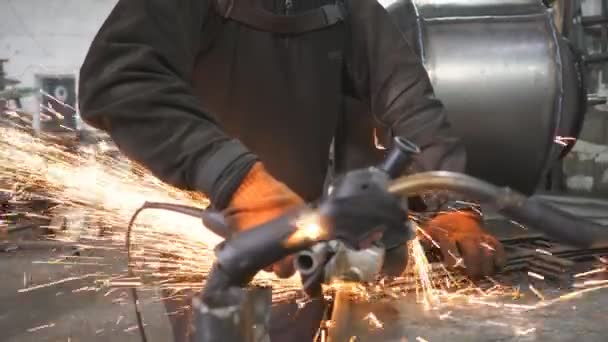 Člověk používá řezací stroj na řezání kovu. Řemeslník s kruhovou pilou v garáži. Profesionální průmyslový dělník brousí kov. Jiskry létají z horkého kovu. Průmyslová výroba. Pomalý mo — Stock video
