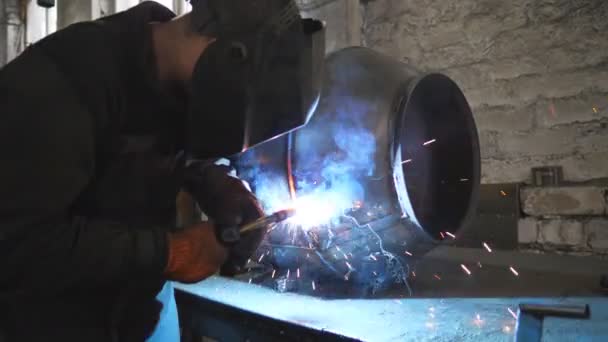 Soldador de soldadura de construcción metálica en la producción de metalurgia industrial. Trabajador en máscara protectora haciendo junta entre dos detalles de acero. Hombre soldando partes del detalle de metal juntos. De cerca. — Vídeo de stock