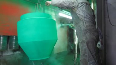 İşçiler boya odasındaki spreyden metal parçalarına boya sıkarlar. Endüstriyel imalatta güvenlik görevlisi. Uzman atölyede usta boya detayı. Yavaşça kapat.
