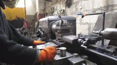 Turner garajda ya da atölyede eski atölyeyle çalışıyor. Tamirci metal işleme için torna kullanıyor. İş yerinde değirmen makinesinde iş. Endüstriyel üretim. Yavaşça kapat.