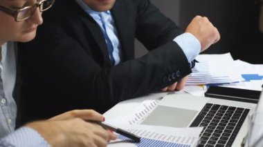 Genç iş arkadaşlarının erkek ve kadın ellerine yakın satış sonuçlarıyla ofisteki dizüstü bilgisayarın grafiğini karşılaştırıyorlar. İş görüşmeleri sırasında mali raporları inceleyen iş arkadaşları