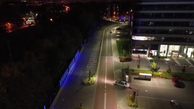 Geceleri modern bir ofis binası boyunca araba sürmek, aydınlanmış çevreleri ve pürüzsüz yol kıvrımlarını gözler önüne sermek, yavaş yavaş uzaklaşıp sahnenin ambiyansını ve hareket akışını gözler önüne sermek.