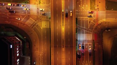 Geceleri hareketli şehir trafiğinin hava görüntüsü, aydınlanmış caddeleri ve hareket halindeki araçları gösterme, kademeli olarak uzaklaşma, canlı şehir manzarasını ve dinamik hareket akışını ortaya çıkarma