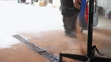 Garaj zeminine emici madde döken tamirci, etkin temizlik süreci gösteren, temiz bir çalışma alanı sağlama ve otomobil servisinde güvenliği sağlama konusundaki kararlılığını gösteren..