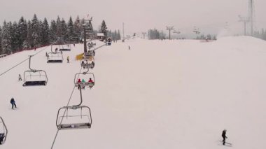 Kayak merkezi sahnesinde kayakçılar karlı yamaçlarda geziniyor, sandalyeler sorunsuz hareket ediyor, macera ve keyif dolu canlı bir kış ortamı yaratıyor.