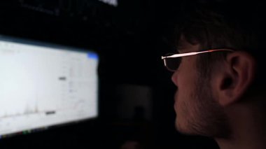 Geceleri bilgisayar üzerinde çalışan finansal analistlerin profili. Erkek tüccar gerçek zamanlı hisse senetleri ve döviz çizelgelerini inceliyor. Akşamları genç analitik ticaret çevrimiçi oluyor. Serbest meslek kavramı.