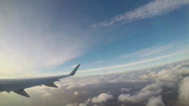 Renkli bir gökyüzünün altında yumuşak bulutların arasında zarif bir şekilde gezinen uçak kanadı, sürekli bir hareketle yeryüzünün üzerinde süzülmenin huzurlu deneyimini resmediyor.