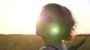 Pembe saçlı mutlu punk kızı gün batımında arpa çayırında kameraya bakıyor. Arka planda buğday yeşili tarlası olan, kulak tünelleri olan gülümseyen hippi kadın portresi. Özgürlük kavramı.