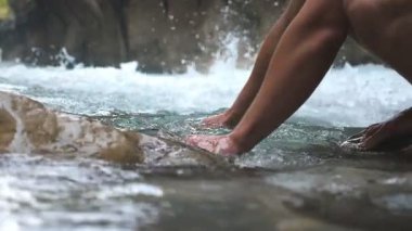 Unrecognizable hiker washing hands in mountain river with clear cool water. Guy standing among river with fast stream and refreshing. Male tourist during his travelling. Slow mo Low view Close up.