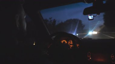 Erkek sürücü direksiyonda el ele tutuşur ve gece vakti otoyolda araba sürer. Adam akşamları modern bir otomobil kullanıyor. Genç adam arazi aracıyla boş yolda hareket ediyor. Yavaşça kapat..