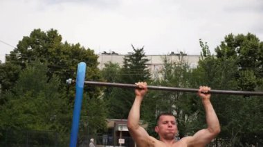 Paralel barlarda dinamik egzersiz yapan sporcu, açık hava eğitim ortamında güç ve kararlılık gösteriyor, atletik gelişimin ve fiziksel kondisyonun özünü yakalıyor..