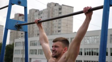 Sporcu dinamik bir barfiks egzersizi yapıyor. Güç ve kararlılık gösteriyor. Açık hava eğitim ortamında kas bağlantısına ve ilerlemeye odaklanıyor..