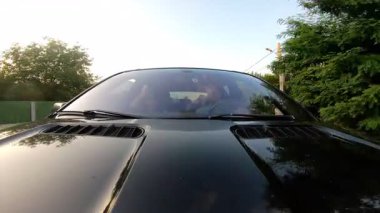 Genç çift iletişim kuruyor ve araba yolculuğunun tadını çıkarıyor. Mutlu erkek ve kadın yaz akşamları araba ile seyahat ederken eğleniyorlar. Yolculuk kavramı. Ön görünümü kapat.