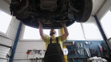 Yetenekli otomotiv teknisyenleri araç şasisi, bakım araçlarından yararlanma, iyi donanımlı bir garaj ortamında organize araçlarla ayrıntılı zanaatkarlık.