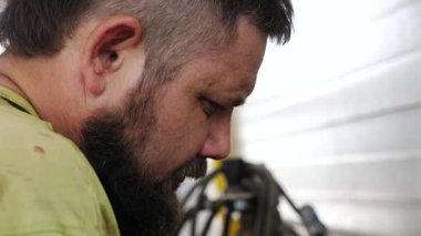 Yetenekli otomotiv teknisyeni, sahnenin orijinalliğini artıran araç gereçler ve ekipmanlarla çevrili profesyonel bir garajda araba tamiri üzerinde çalışırken odaklanma ve hassasiyet gösteriyor.